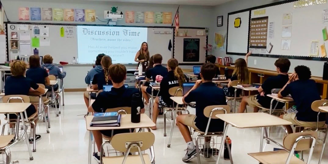 An Ethics Lab session in a middle-school classroom, the board reading Discussion Time and asking whether AI has ever helped you make something you could not have made alone, one student with a hand raised
